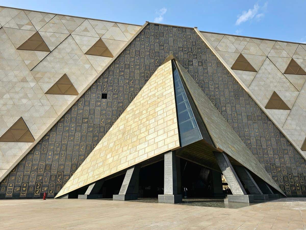 Eingang des Grand Egyptian Museum in Gizeh mit moderner Architektur und Hieroglyphenwand.