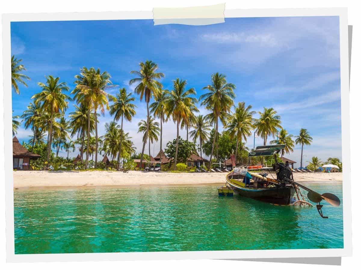 Strand auf Koh Mook in Thailand mit Palmen, Longtailboot und türkisfarbenem Meer