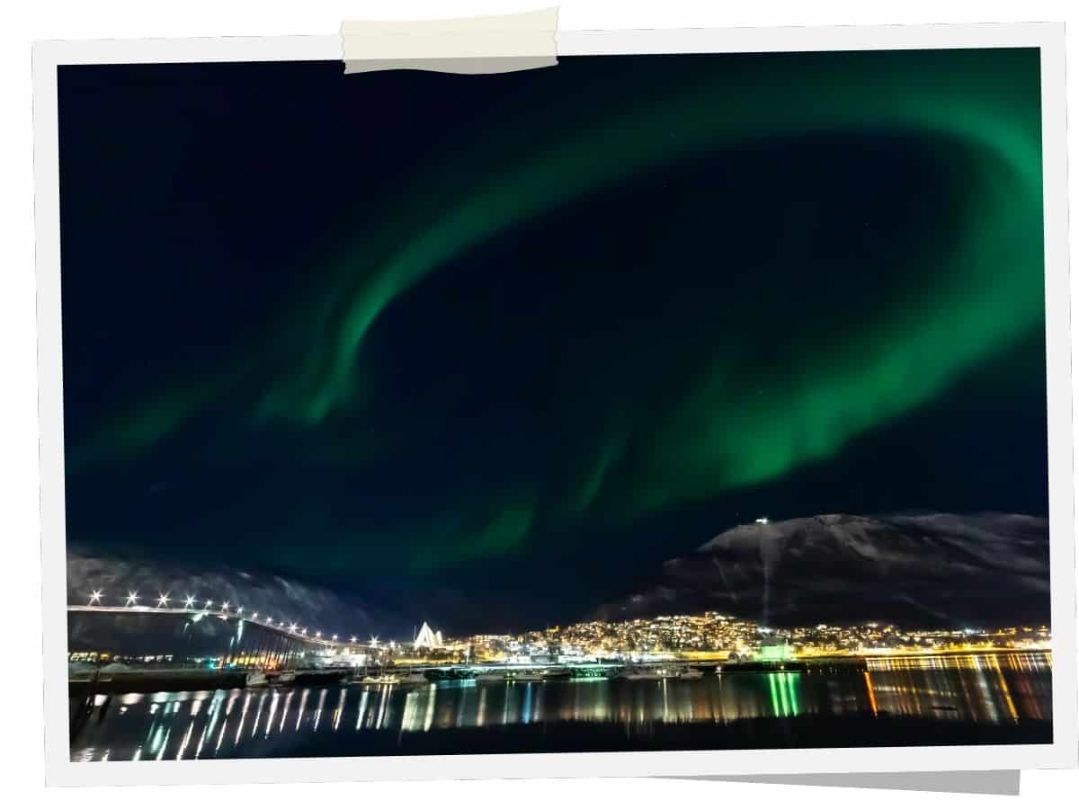 Polarlichter über Tromsø mit Blick auf die Eismeerkathedrale und den Hafen bei Nacht