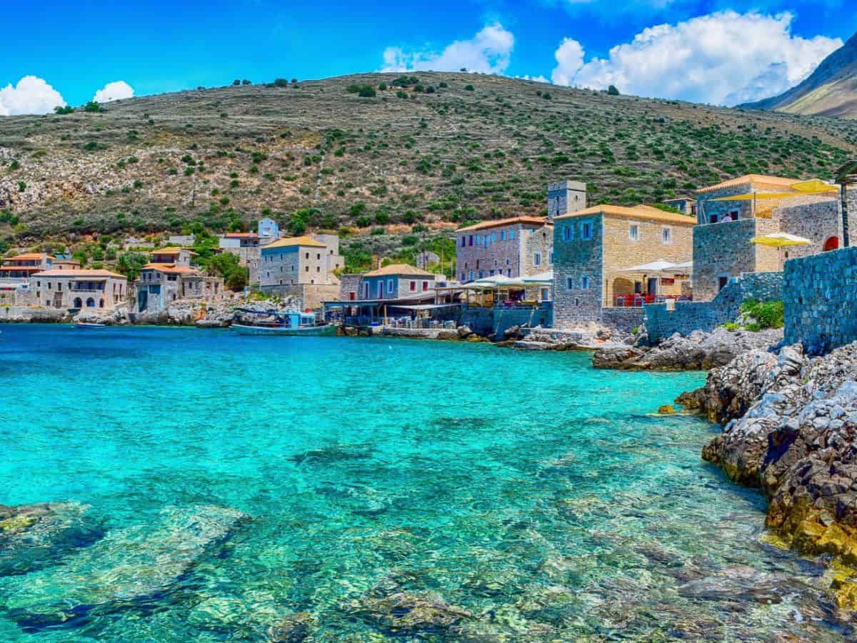 Küstendorf Limeni in Lakonien auf dem Peloponnes in Griechenland mit traditionellen Steinhäusern und kristallklarem türkisblauem Meer an einer felsigen Buch