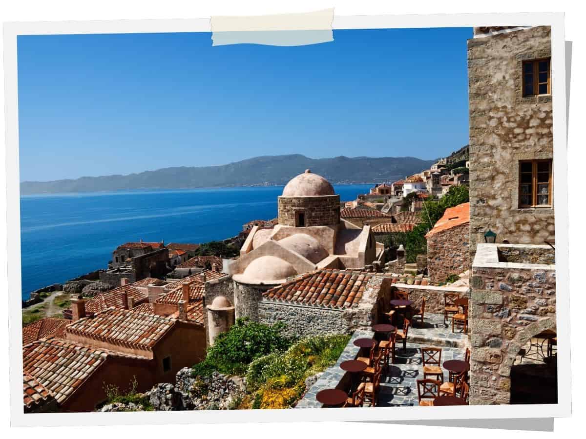 Blick über die historische Altstadt von Monemvasia auf dem Peloponnes mit Natursteinhäusern, byzantinischer Kirche und dem tiefblauen Myrtoischen Meer.