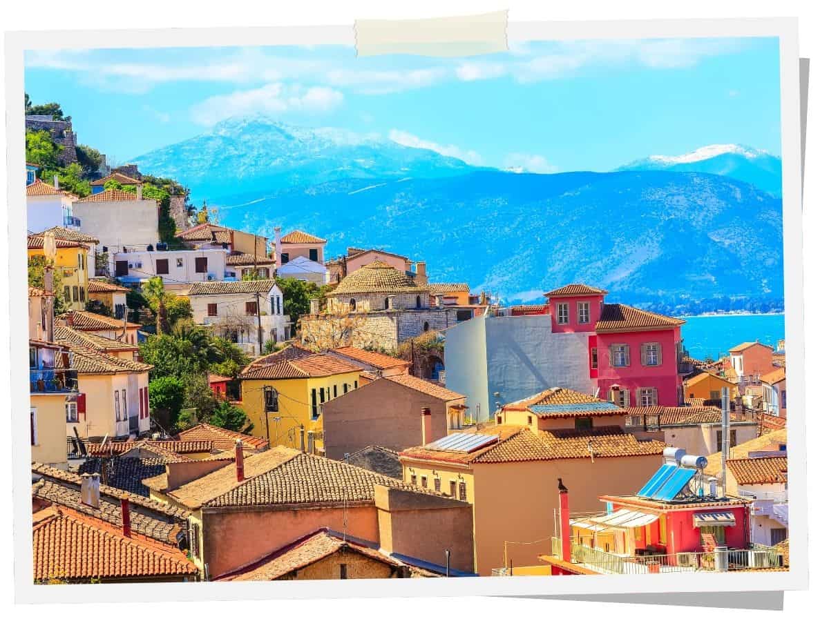 Blick auf die Altstadt von Nafplio auf dem Peloponnes mit bunten Häusern, roten Ziegeldächern und Bergen im Hintergrund.