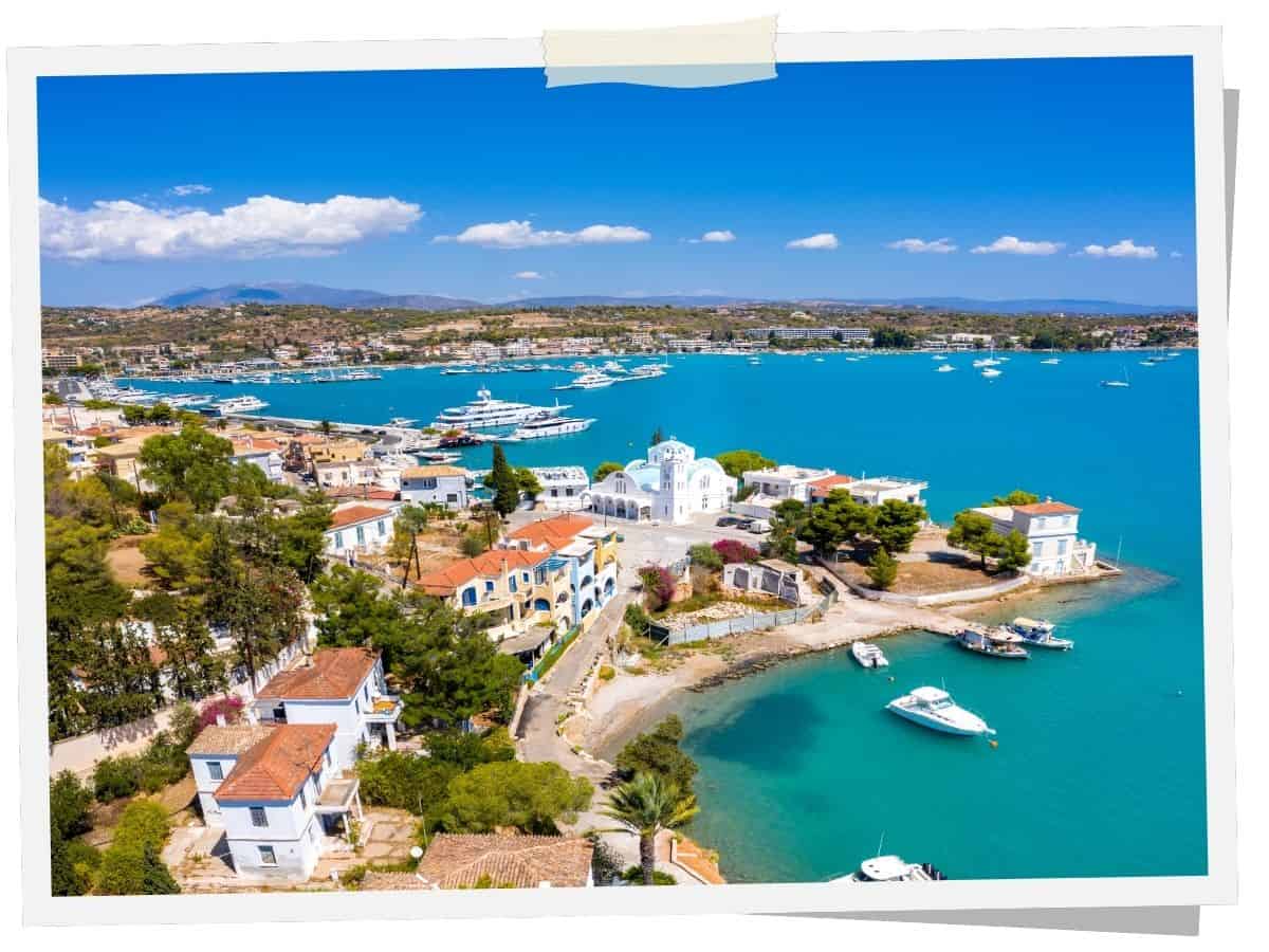 Luftaufnahme von Porto Heli am Saronischen Golf auf dem Peloponnes mit Yachthafen, weißen Häusern und türkisblauem Meer.