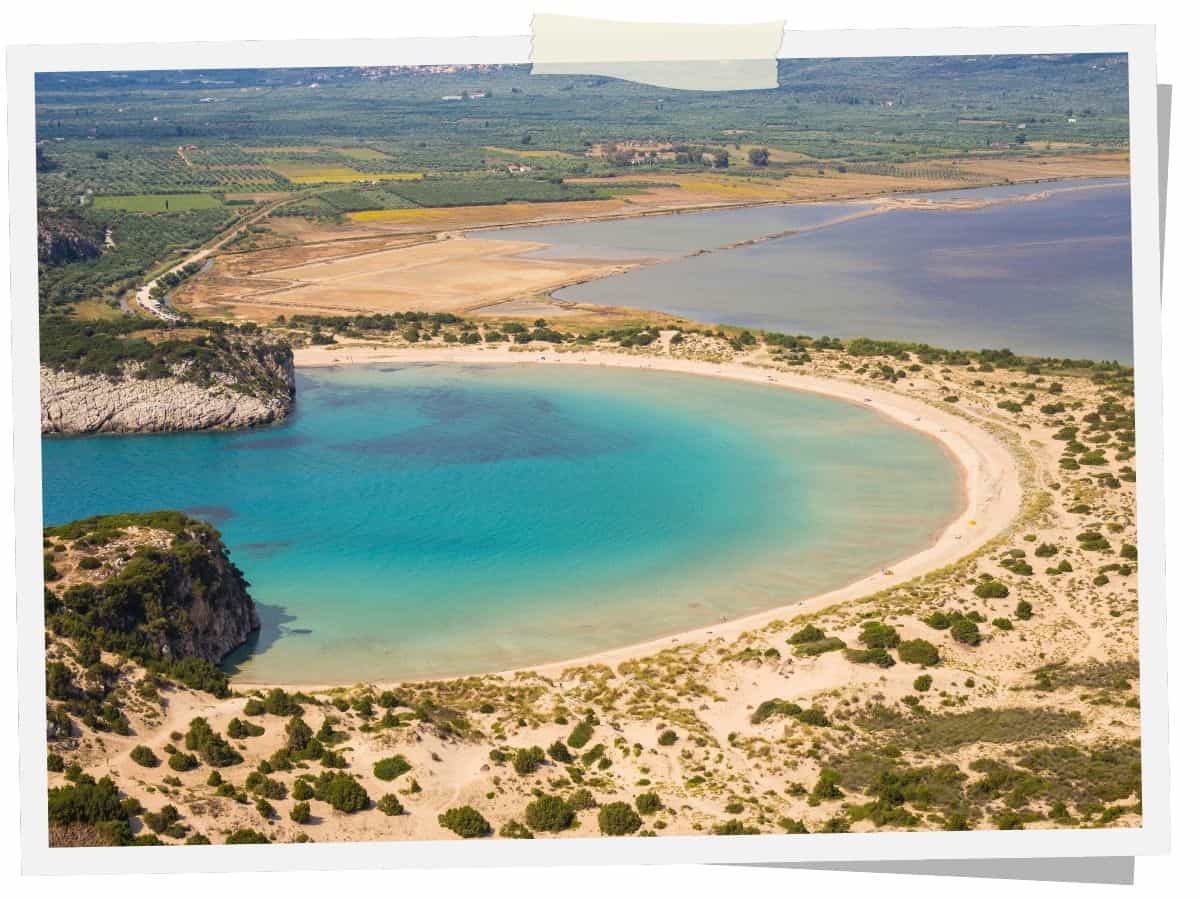 Voidokilia-Strand in Messenien auf dem Peloponnes mit halbkreisförmiger Sandbucht, türkisblauem Wasser und Dünenlandschaft.
